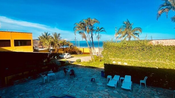 Ein Poolbereich mit Liegestühlen und freiem Blick auf das Meer.