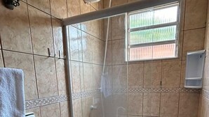 Eine Dusche mit Glastür, einem Handtuchhalter und einem Fenster mit Aussicht.