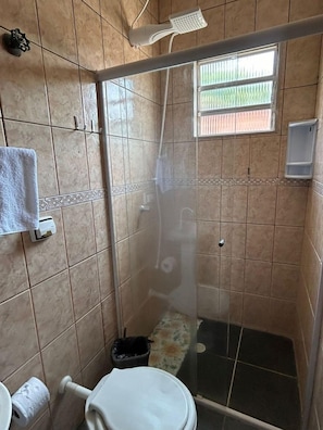 Une douche avec une porte en verre, un porte-serviettes et une fenêtre donnant sur un beau paysage.