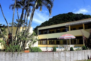 Un bâtiment à deux étages doté d’une piscine, entouré de palmiers et d’un mur de pierre.