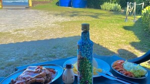 Eine Mahlzeit auf einem Tisch im Freien mit Blick auf das Meer und üppige Vegetation.