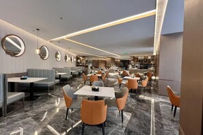 A modern restaurant with round mirrors on the walls, marble flooring, and a mix of table and booth seating. - Microtel by Wyndham Changsha Xingsha (Changsha)