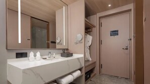 Un baño moderno con un lavabo de mármol, dos espejos, una bata y un perchero para toallas.