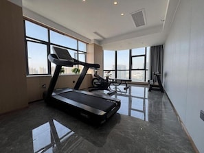 A modern gym with a treadmill, stationary bikes, and a large window offering a city view. - Microtel by Wyndham Changsha Xingsha (Changsha)