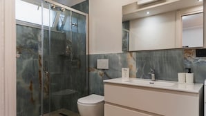 Een moderne badkamer met een douchecabine van glas, een wit toilet en een wastafel met spiegel.