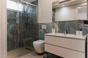 Un bagno moderno con doccia vetro, un water bianco e un mobile lavabo con specchio.