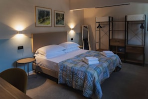Una camera d'albergo con un letto, comodini, uno specchio e un letto a castello.