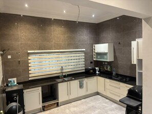 A modern kitchen with a built-in oven, a sink, and a stove. -  Heritage Comfort & Peace, Your Perfect Getaway. Self compound, gated house (Accra)