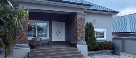Et moderne hus med to etager, en veranda, en søjle af sten og en garageport.