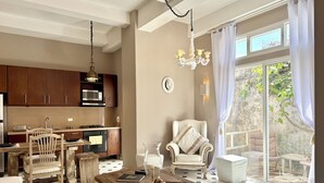 Una cocina moderna con armarios de madera, un comedor con mesa de madera y vista a un jardín a través de puertas correderas grandes.