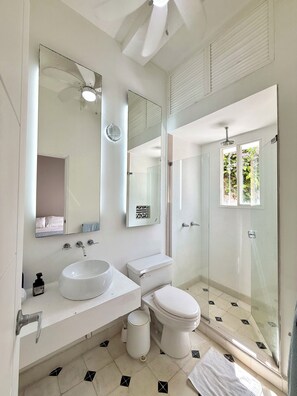 A modern bathroom with a large mirror, two sinks, a toilet, and a glass shower enclosure. - by Calamari.Homes - Centenario 304 - Old City (Cartagena de Indias)