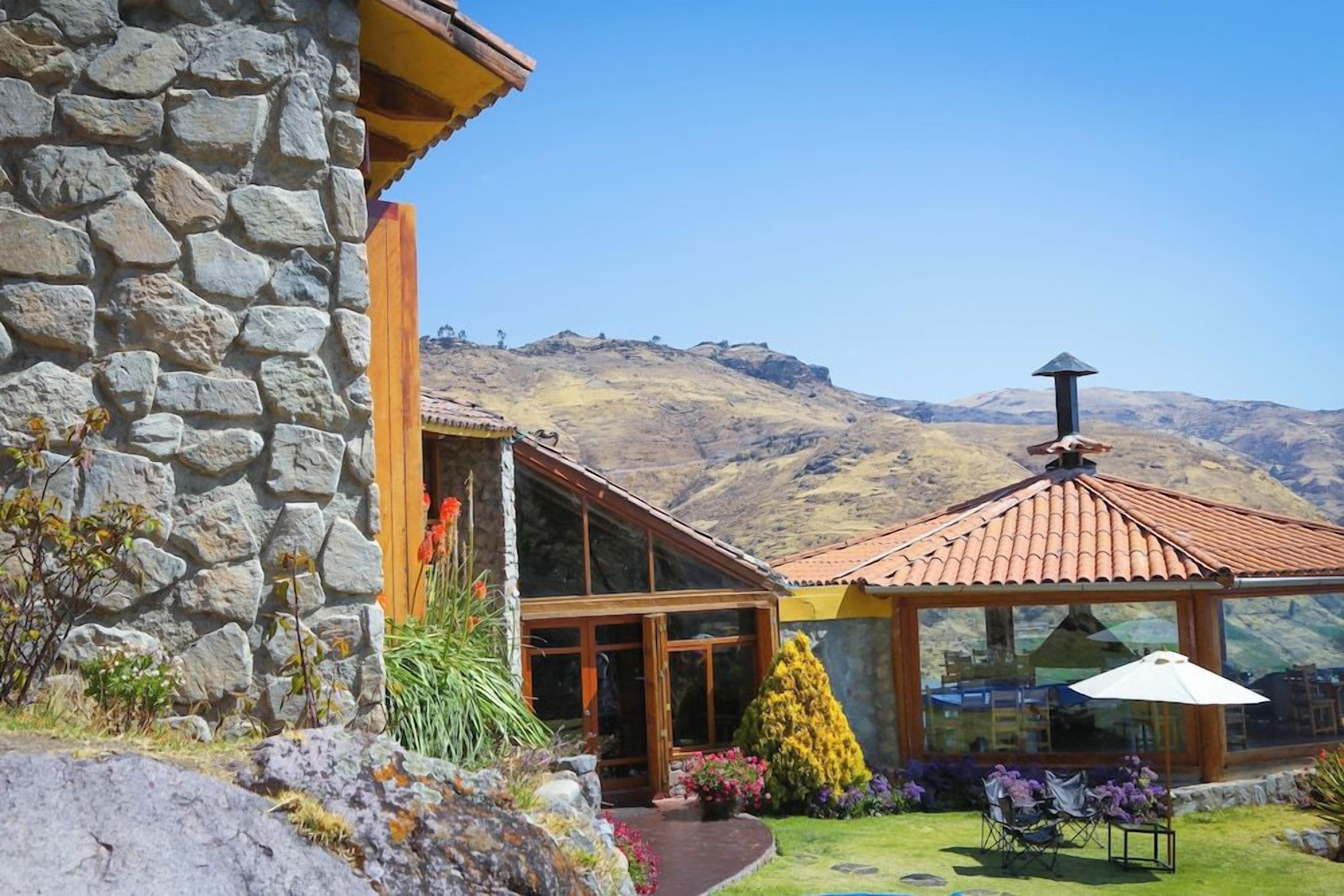 Un edificio de piedra con entrada de madera y una estructura de cristal con tejado de tejas.