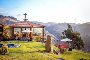 A house with a glass-enclosed patio, outdoor seating, a swimming pool, and a view of mountains.