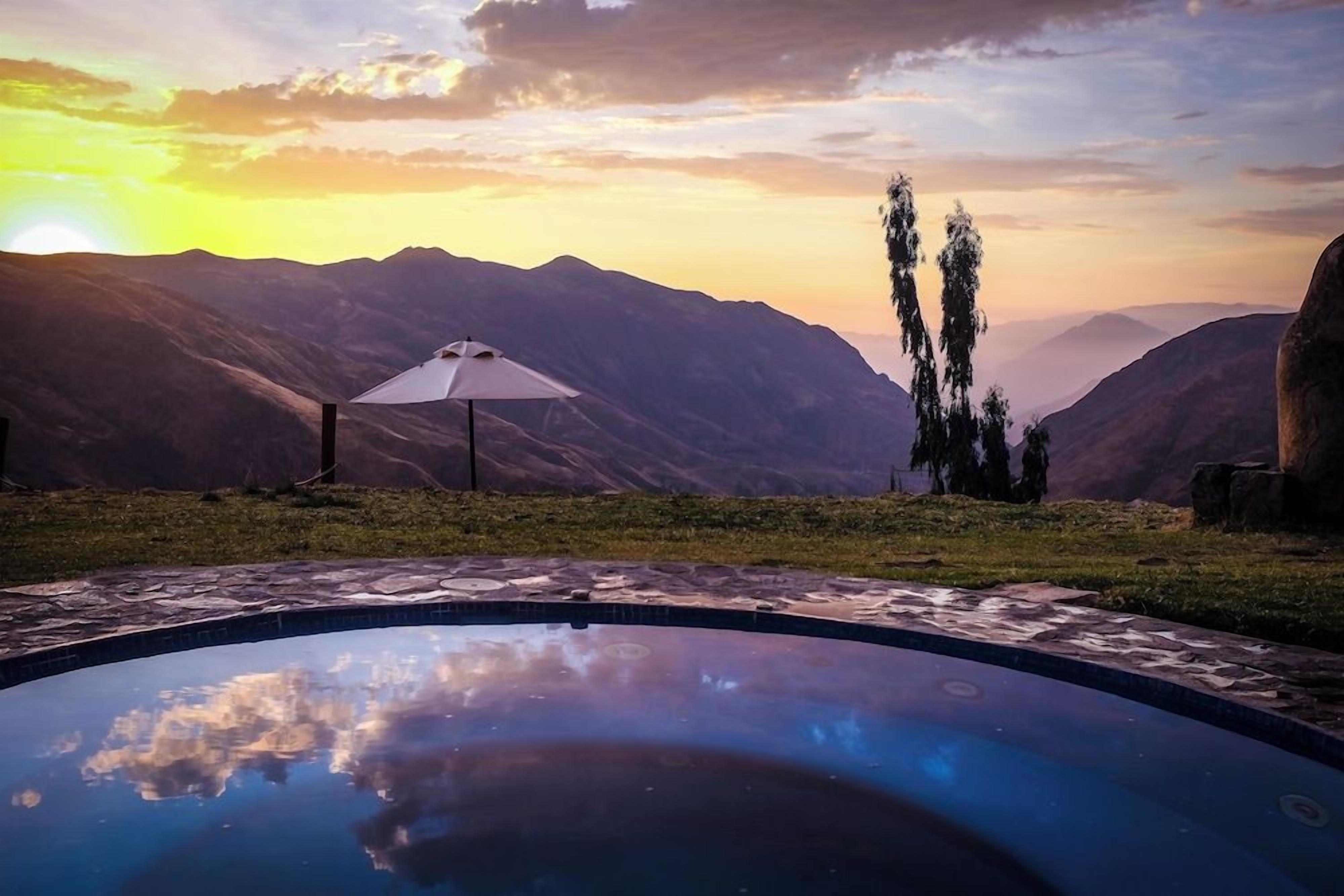 Una piscina con vista a las montañas durante el atardecer.