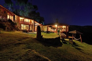 A two-story stone building with a balcony, outdoor seating, and a well-lit patio area. - Refugio Vinak (Vinac)