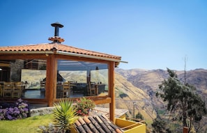 A wooden gazebo with a glass enclosure overlooking a mountainous landscape.