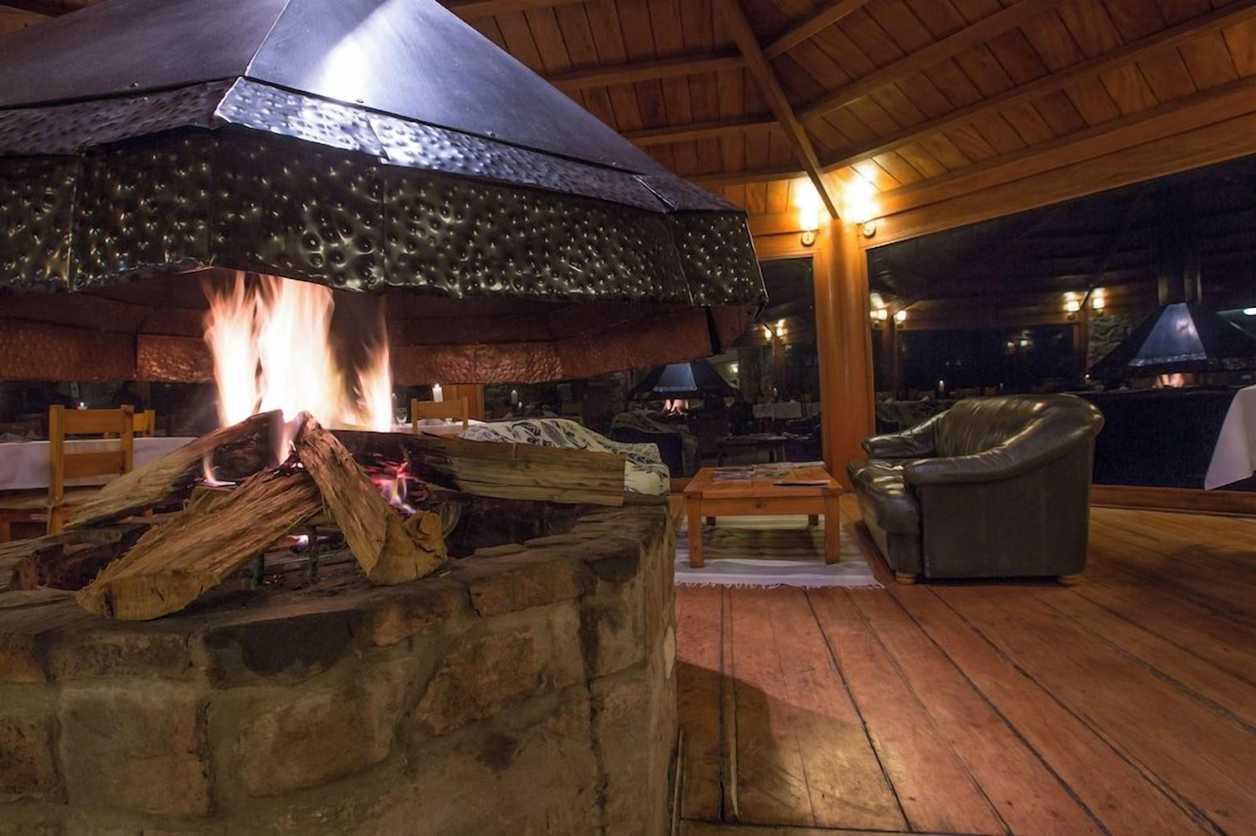 Un espacio al aire libre con una chimenea de piedra, una parrilla metálica y un sofá de cuero.