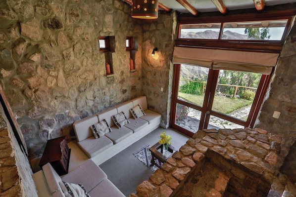 A stone-walled room with a sofa and a stone fireplace. - Refugio Vinak (Vinac)