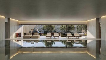 Un interior moderno con piso reflectante, ventanas amplias y una zona de estar con sofás y sillones.