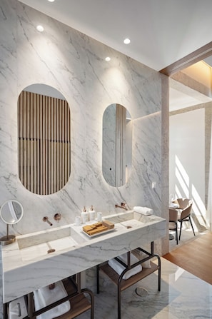 Un baño moderno con tocador de mármol, dos lavamanos y un espejo grande.