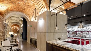 A modern kitchen with marble countertops, red cabinets, and a brick ceiling. - The Lince Santa Clara Historic Hotel (Vila do Conde)