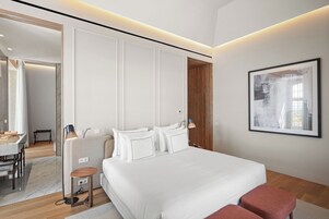 Un dormitorio moderno con una cama grande, mesitas de noche, un escritorio y una silla.
