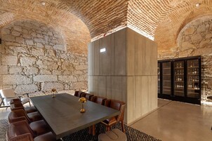 Uma sala de conferência com uma mesa comprida, cadeiras de couro e uma parede de pedra.