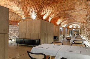 Un restaurante con techos abovedados de ladrillo, paneles de madera y mesas dispuestas para comer.