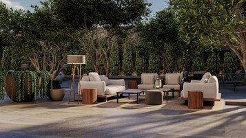 Un espacio al aire libre con sofás, mesas y una lámpara.