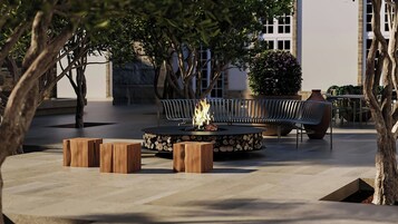 An outdoor seating area with a round table, benches, and a fire feature.