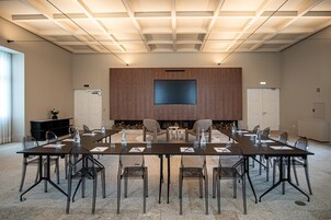 A conference room with a long table, chairs, a flat-screen TV, and a fireplace.