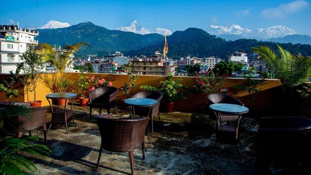 A rooftop terrace with outdoor seating, potted plants, and a view of snow-capped mountains. - Hotel Hidden Kingdom & Spa (Pokhara)