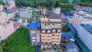 A multi-story hotel with a central courtyard, surrounded by other buildings, near a body of water. - Hotel Hidden Kingdom & Spa (Pokhara)