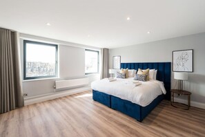 A modern bedroom with a large bed, a view through the window, and a cityscape.