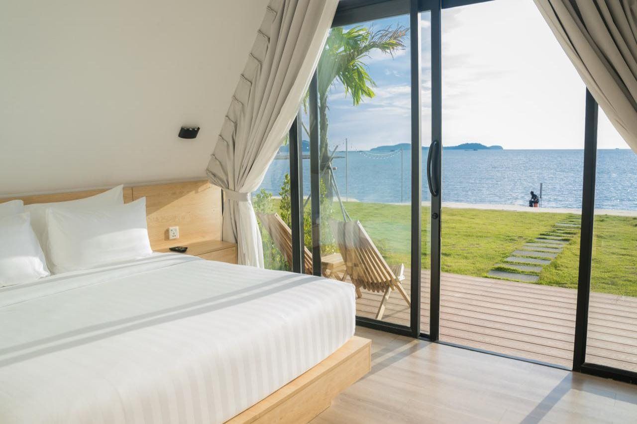 Een slaapkamer met een groot bed, uitzicht op zee en een terras met een stoel.