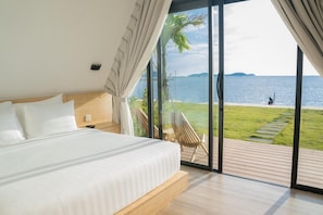 Un dormitorio con una cama grande, vistas al mar y una terraza con una silla.