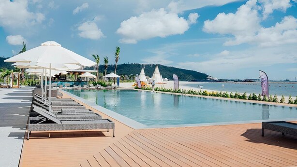 A poolside area with lounge chairs, umbrellas, and a view of the sea. - Summer Bay Beach Club and Cabins Sihanoukville by Preference (Prey Nob)