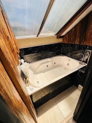 Un ba ño con bañera, paneles de madera y un tragaluz.