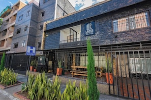 A hotel named 'LARES DE LA 70' with a stone facade, outdoor seating area, and a visible entrance. - Hotel Lares 70 (Medellín)