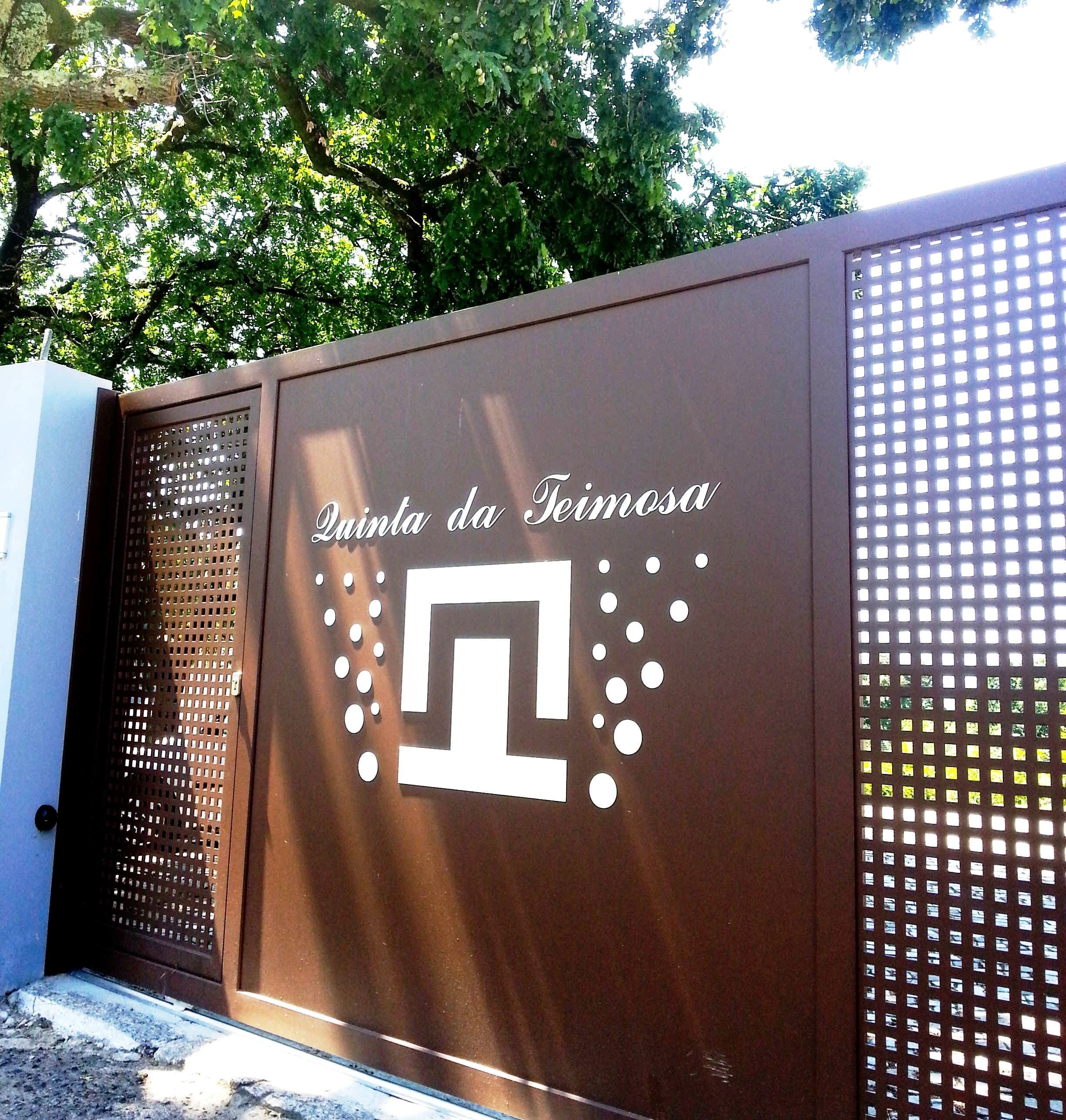 Une grille en métal ornée d’un logo et de l’inscription « Quinta da Teimosa ».