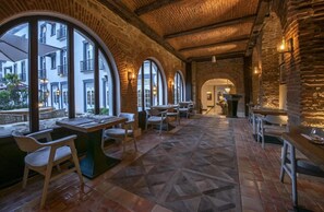 A restaurant with brick walls, arched windows, and a patterned floor. - Hotel La Compania In The Unbound Collection By Hyatt (Panama City)