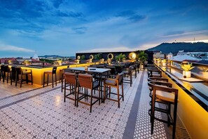 An outdoor dining area with tables and chairs, a patterned floor, and a view of a hill in the background. - Hotel La Compania In The Unbound Collection By Hyatt (Panama City)