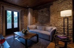 A cozy room with a stone wall, a sofa, a coffee table, a floor lamp, and a bench. - Hotel La Compania In The Unbound Collection By Hyatt (Panama City)