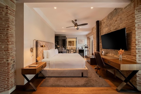 A modern hotel room with a large bed, a desk, a chair, a television, and a ceiling fan. - Hotel La Compania In The Unbound Collection By Hyatt (Panama City)