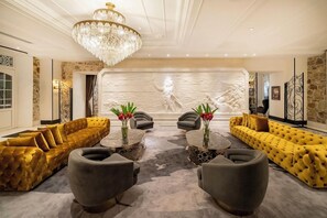 A luxurious lobby with a grand chandelier, plush yellow sofas, and a marble wall with a relief sculpture. - Hotel La Compania In The Unbound Collection By Hyatt (Panama City)