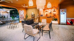 Uma área de recepção com sofá, cadeiras, mesa e refrigerador.