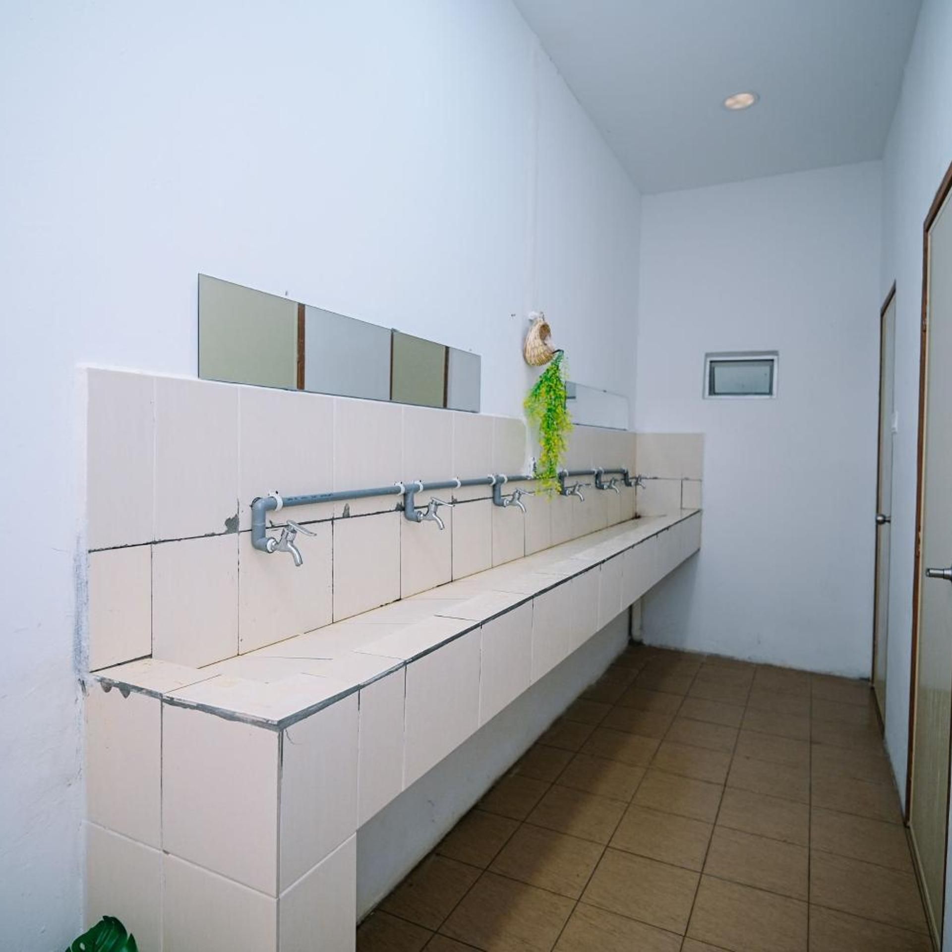A public restroom with a long bench, a hand dryer, and a mirror on the wall.