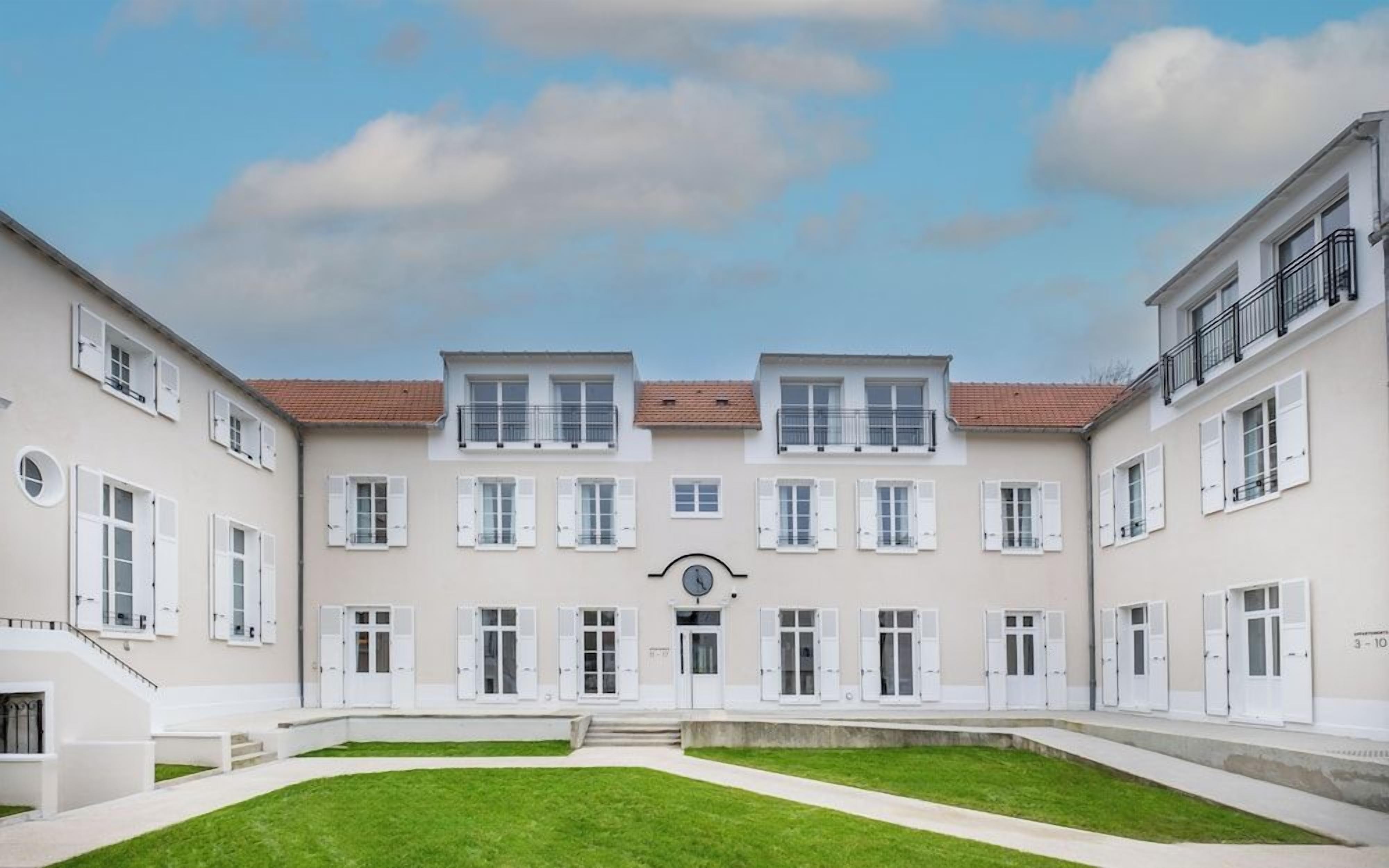 A symmetrical building with a central courtyard, multiple windows, and a clock.