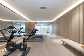 A modern gym with treadmills, a stationary bike, and a bench. - Ji Hotel (Wuhan)