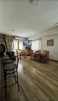 Un comedor con sillas y mesas de madera, una pared de piedra y un televisor fijado a la pared.